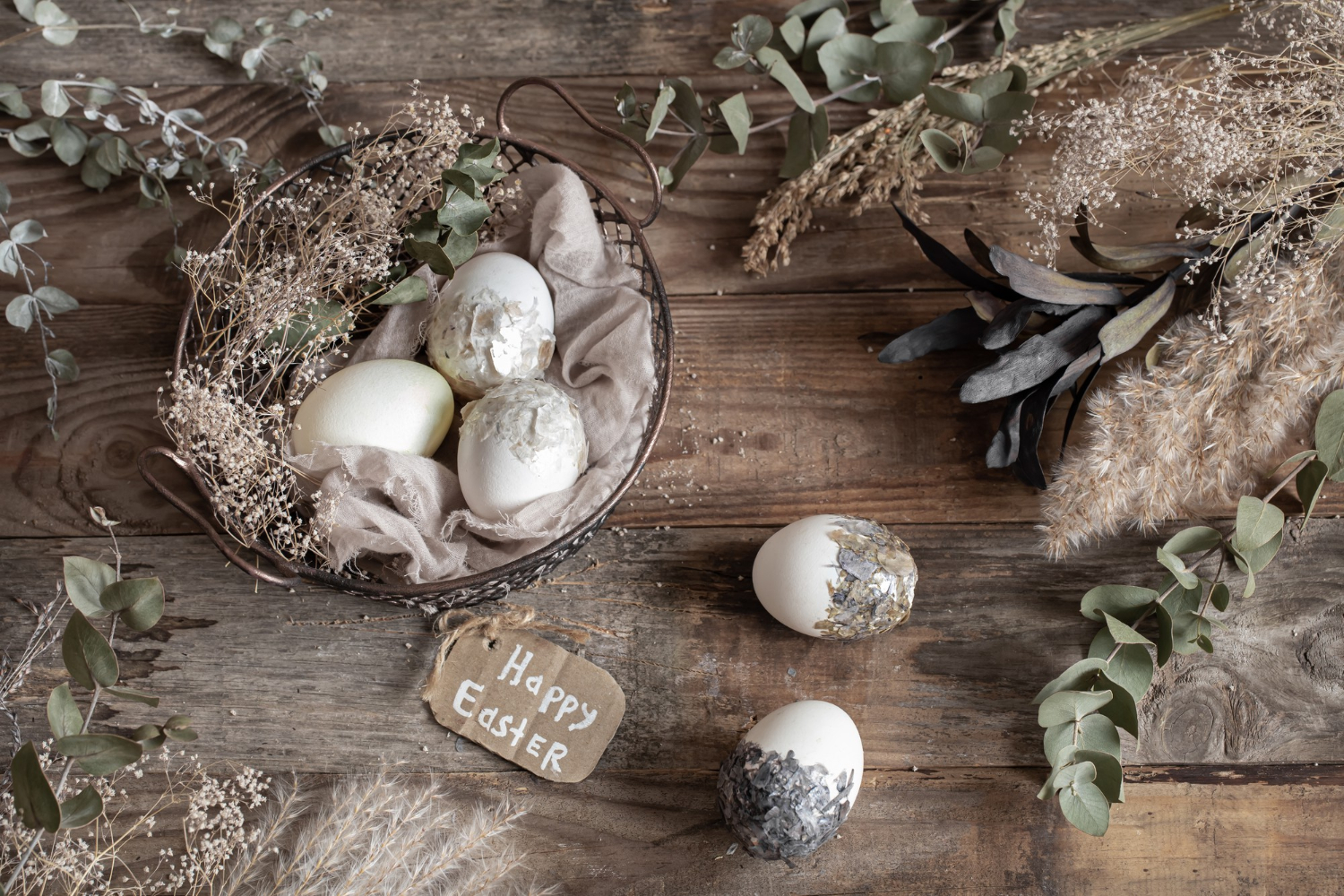 easter-eggs-in-a-decorative-basket-with-dried-flowers-on-a-wooden-table-happy-easter-concept